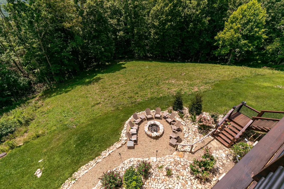 A landscaped stone fire pit surrounded by comfortable seating and lush greenery—an inviting spot for gathering, storytelling, and enjoying the outdoors, especially under the stars.