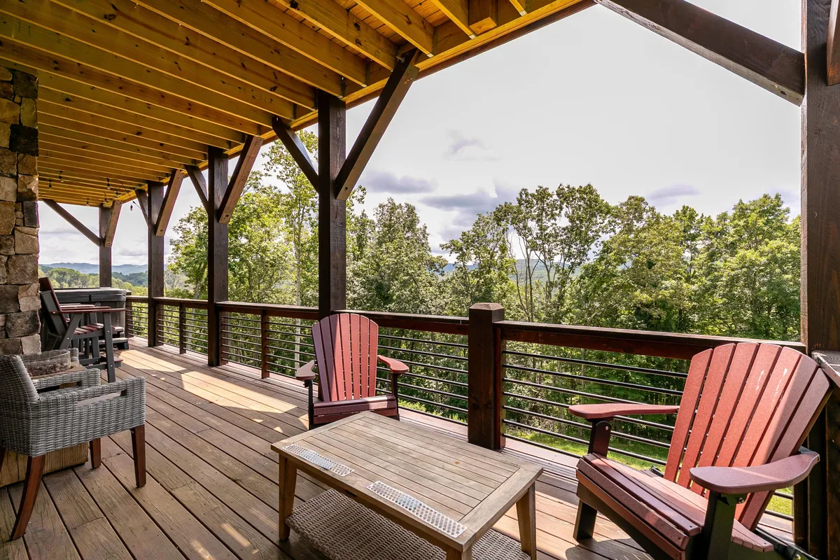 A wooden deck with Adirondack chairs and stone columns, offering panoramic mountain views. The setting is tranquil, suggesting relaxation, social gatherings, and enjoyment of the natural world in every season.