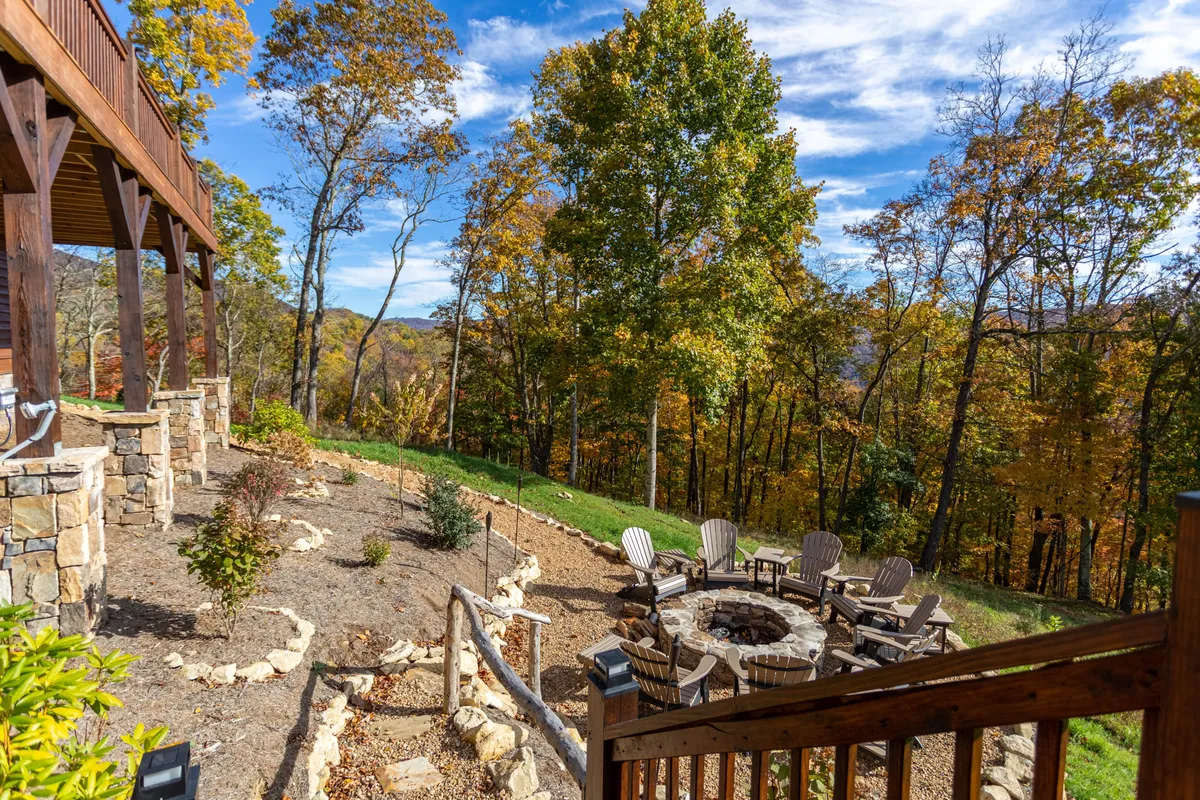 A cozy fire pit area sits on a wooden deck surrounded by trees, offering a comfortable spot to gather outdoors. The deck is spacious, well-maintained, and blends seamlessly with the natural setting, providing plenty of secure, open space for dogs and people alike.